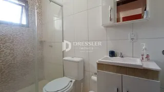 Foto interna de um banheiro com revestimento cerâmico e box de vidro.