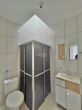 Foto de um banheiro com revestimento cerâmico e box de vidro.