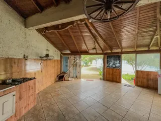 Ambiente interno de uma sala ampla com teto de madeira e piso de cerâmica.