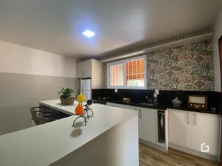 Cozinha moderna com armários brancos e bancadas escuras.