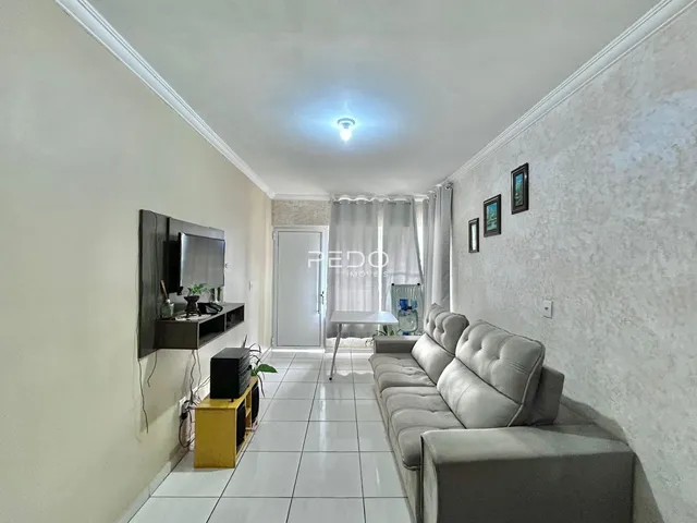 Sala de estar com sofá e televisão em um ambiente claro.