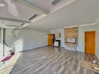 Sala de estar ampla com piso de porcelanato e parede de destaque na residência.