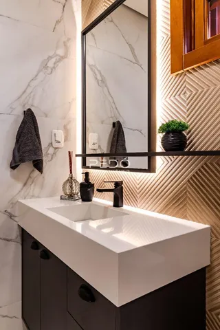 Banheiro com bancada branca e espelho decorativo.