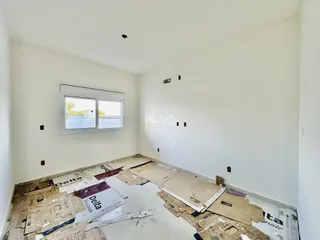 Imagem de um cômodo interno em reforma com piso coberto de materiais.