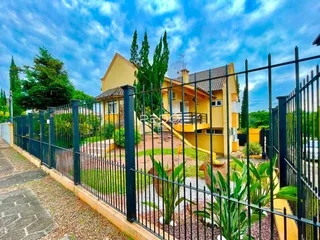 Fachada de uma casa amarela em Lajeado, Brasil, com cerca e jardim.