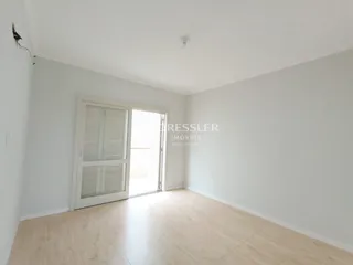 Ambiente interno com piso de madeira clara e paredes brancas.