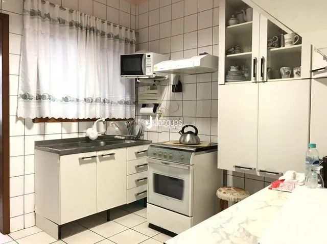 Foto de uma cozinha com armários brancos e piso de cerâmica.