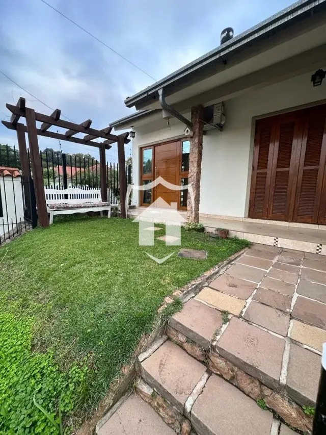 Vista da fachada de uma residência com cerca de madeira e jardim.