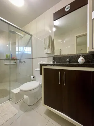 Um banheiro moderno com box de vidro e revestimento cerâmico.