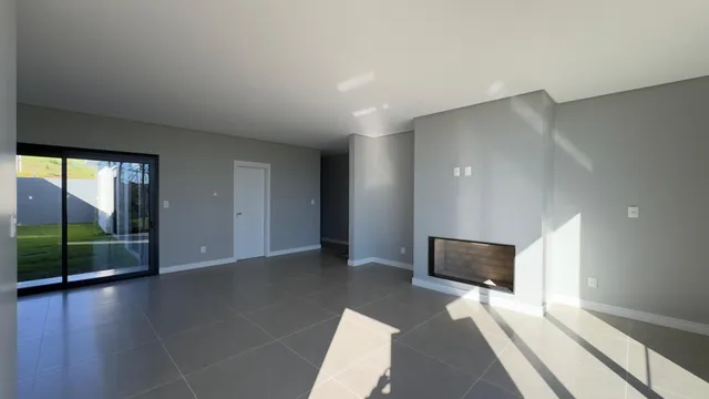 Ambiente interno amplo com piso claro e porta de vidro que dá acesso ao exterior.