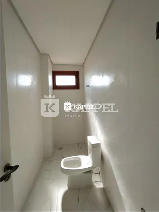 Corredor estreito com um vaso sanitário branco em um imóvel.