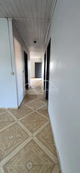 Corredor interno com piso de cerâmica claro e paredes brancas.
