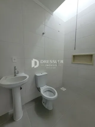 Foto de um banheiro com revestimento branco e louças sanitárias.