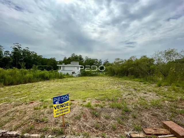 Vista externa de uma propriedade com terreno gramado e vegetação ao fundo.
