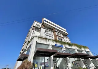 Foto da fachada de um prédio residencial em Lajeado, Brasil, com vegetação no topo.