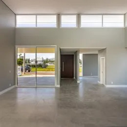 Foto de um espaço interno com piso de concreto e portas de vidro.