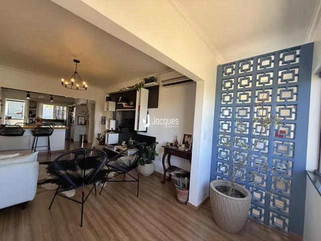 Sala de estar com piso de madeira e parede decorativa azul em um imóvel em Lajeado.