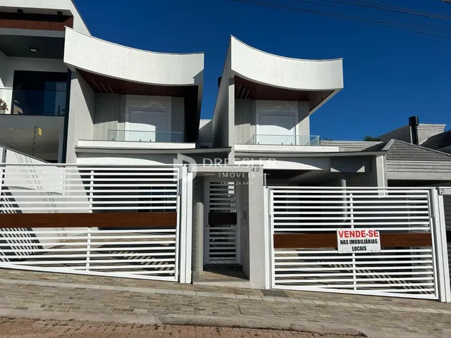 Fachada moderna de uma residência em Lajeado, Brasil, com portão de ferro branco.