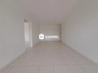 Corredor longo com piso de cerâmica e paredes brancas.