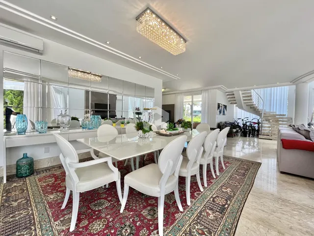 Sala de jantar ampla com mesa e cadeiras brancas em um ambiente iluminado.