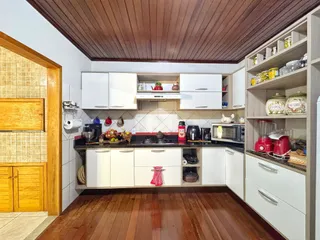Cozinha com armários brancos e piso de madeira em Lajeado, Brasil.