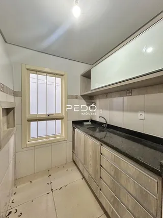 Uma cozinha com armários e janela em um imóvel no Brasil.