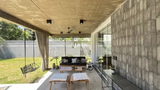 Vista de uma área externa coberta com mobiliário de lazer e gramado.