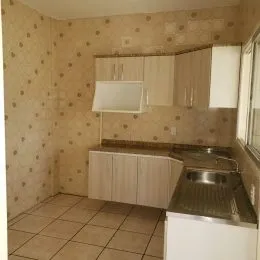Foto interna de uma cozinha com armários superiores e bancada.