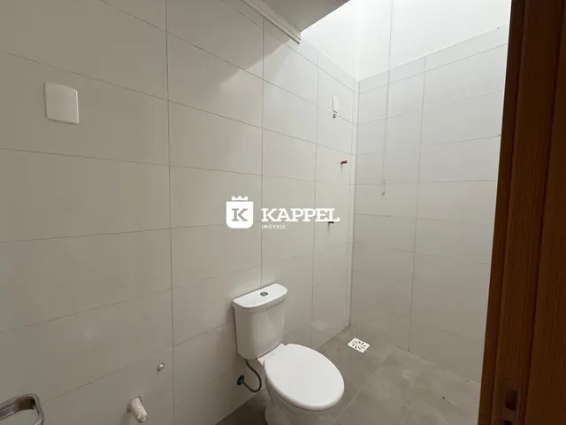 Foto interna de um banheiro com paredes brancas e piso de azulejo claro.