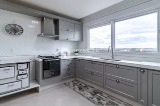 Cozinha moderna com armários cinzas e piso claro em um imóvel em Lajeado.