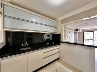 Cozinha moderna com armários brancos e bancadas pretas.