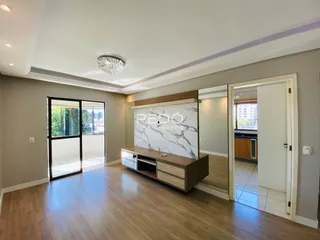 Sala de estar com piso de madeira e portas de vidro que dão acesso ao exterior.