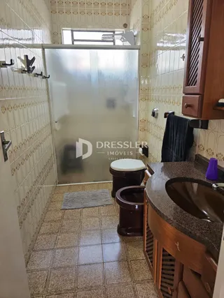 Foto de um banheiro com revestimento de azulejos brancos e piso de cerâmica.