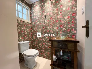 Foto de um banheiro com revestimento de papel de parede floral e um vaso de madeira.