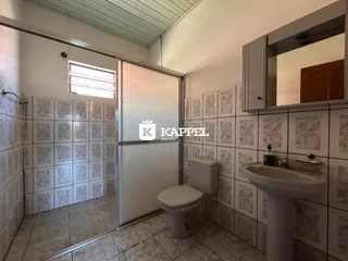 Banheiro com revestimento de azulejos brancos e louças brancas.