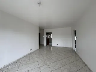 Vista interna de um corredor com paredes brancas e piso de cerâmica.