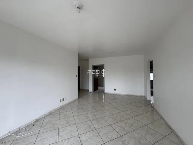 Vista interna de um corredor com paredes brancas e piso de cerâmica.