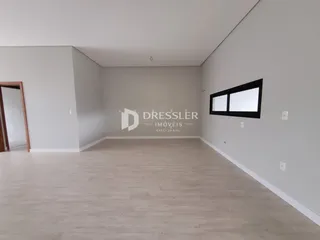 Ambiente interno de uma sala com piso claro e paredes brancas.