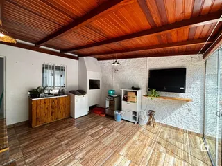 Sala de estar com piso de cerâmica e teto de madeira aparente.