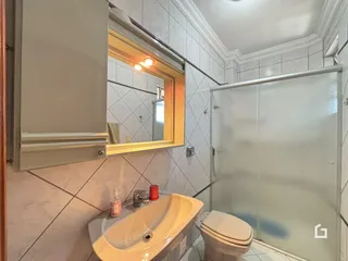 Foto de um banheiro com azulejos brancos e box de vidro.
