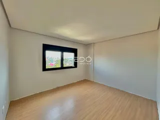 Ambiente interno de uma sala com piso de madeira clara e janela.