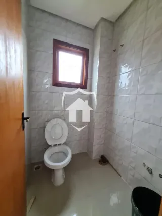 Banheiro com revestimento cerâmico branco nas paredes e piso claro.