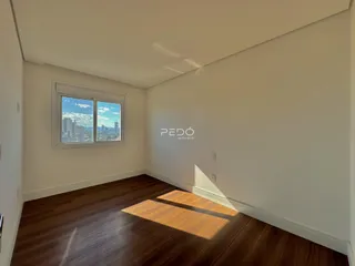 Ambiente interno com piso de madeira e janela de vista para a cidade.