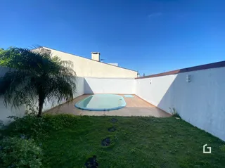 Vista externa de uma piscina e jardim em uma propriedade.