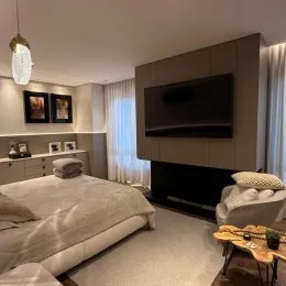 Quarto com cama grande e televisão montada na parede.