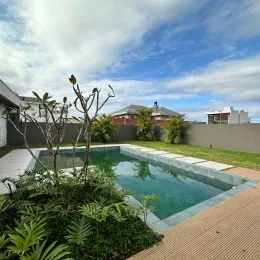 Foto da piscina externa com área verde ao redor.