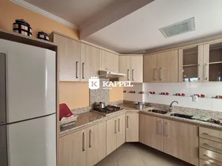 Cozinha com armários de madeira clara e bancadas.