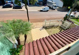 Vista externa de uma propriedade com jardim e cerca de madeira.