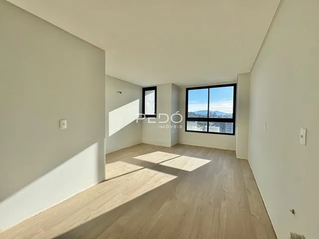 Vista interna de uma sala com piso de madeira clara e paredes brancas.