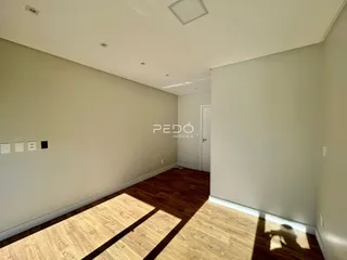Interior de uma sala com piso de madeira e paredes claras.